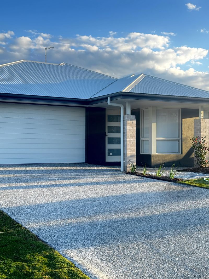 Freshly clear-sealed exposed-aggregate driveway and path on a new build home