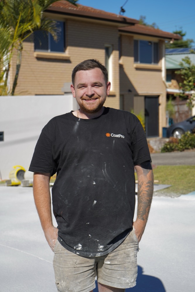 A CoatPro applicator smiling on a freshly sealed pool surround