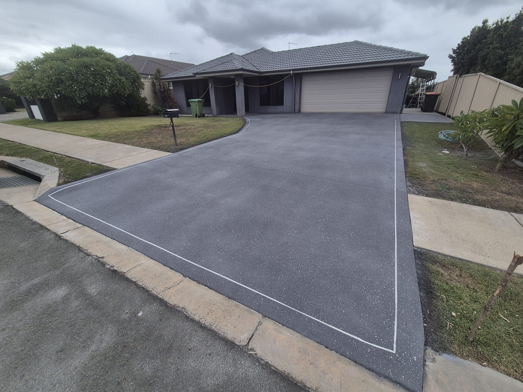 Dark grey driveway resurfaced in Blue Mountain colour with a white fleck finish at a single-storey home in Raceview