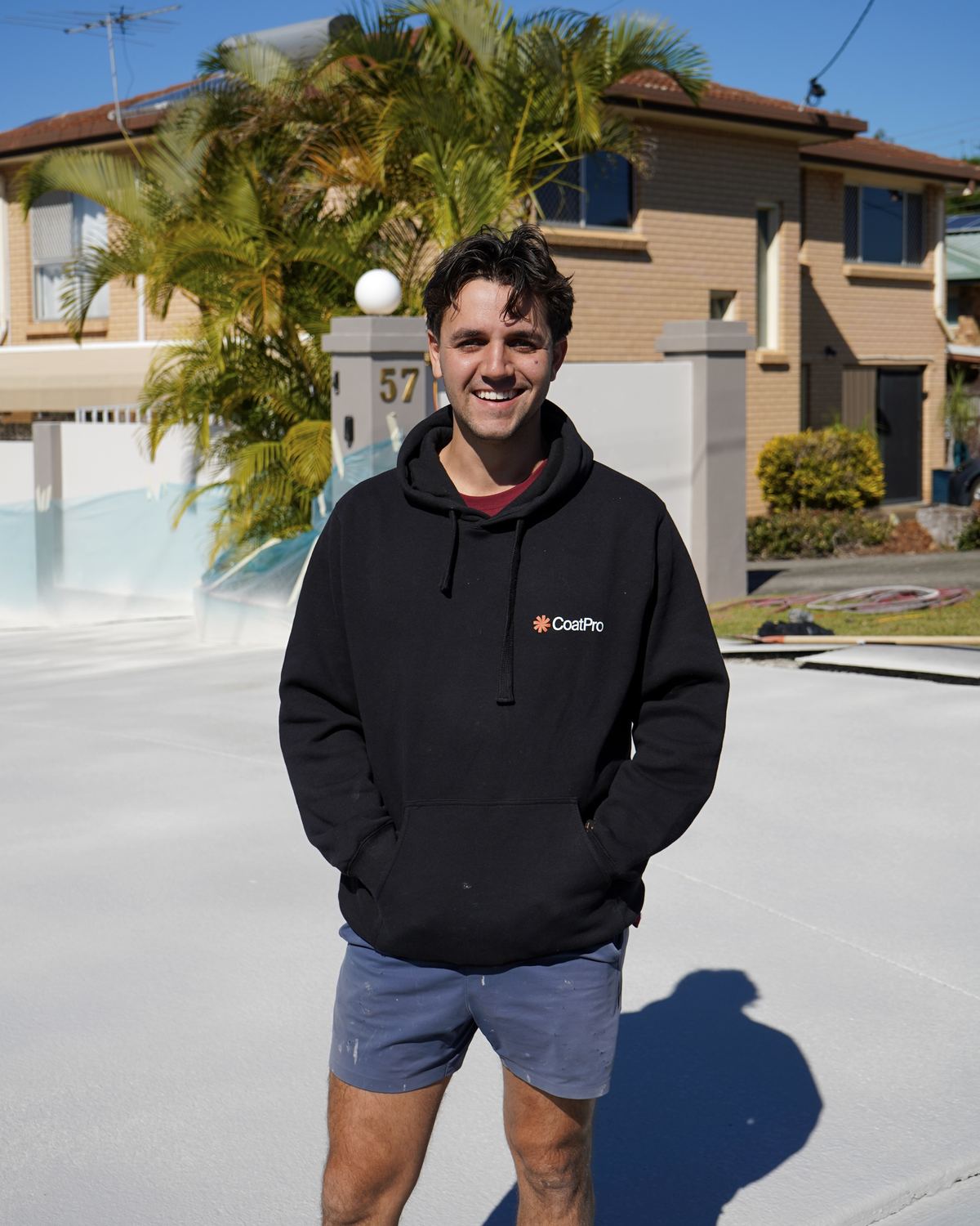 Lachlan smiling in a CoatPro hoodie on a freshly coated pool surround