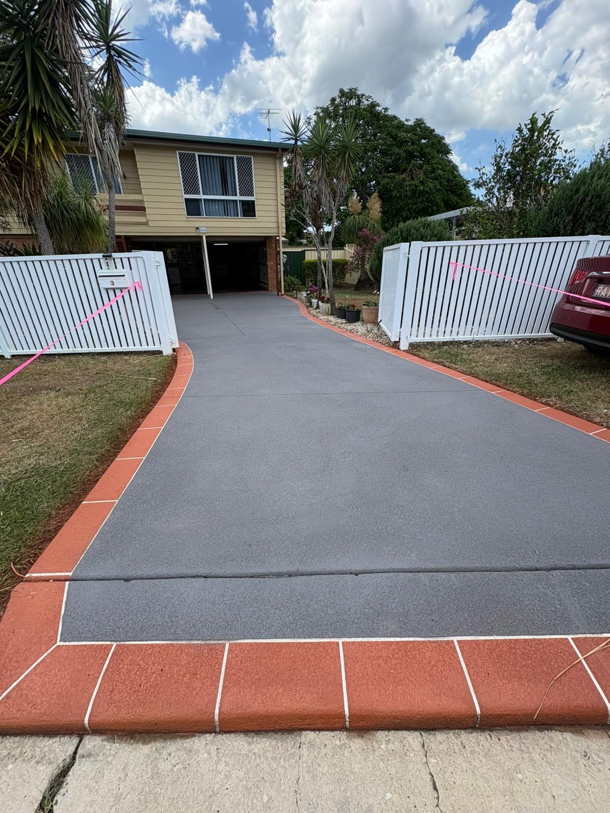 After: the same driveway resealed in Coal with a Terracotta border